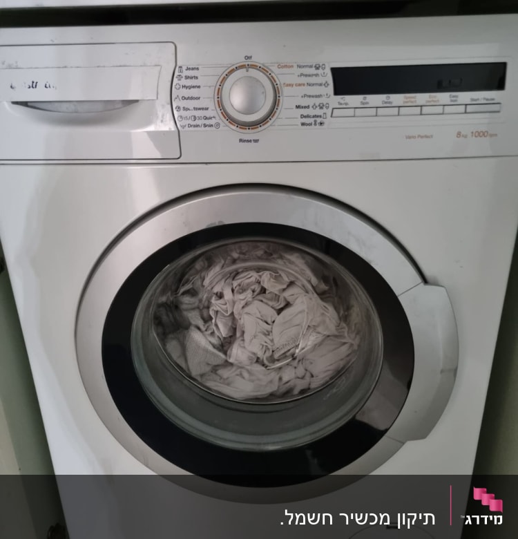 מכונת כביסה עם בגדים בתוף ותצוגת כפתורים